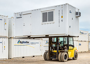 Forklift moving a shipping container office